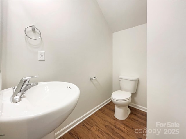 bathroom featuring hardwood / wood-style floors, toilet, lofted ceiling, and sink