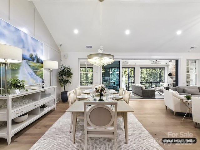 dining room featuring hardwood / wood-style floors, lofted ceiling, a wealth of natural light, and an inviting chandelier