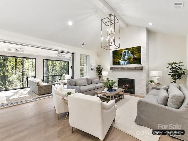 living room with a fireplace, lofted ceiling with beams, light hardwood / wood-style floors, and a notable chandelier