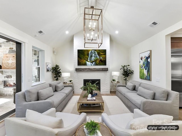 living room with a fireplace, light hardwood / wood-style flooring, vaulted ceiling, and an inviting chandelier