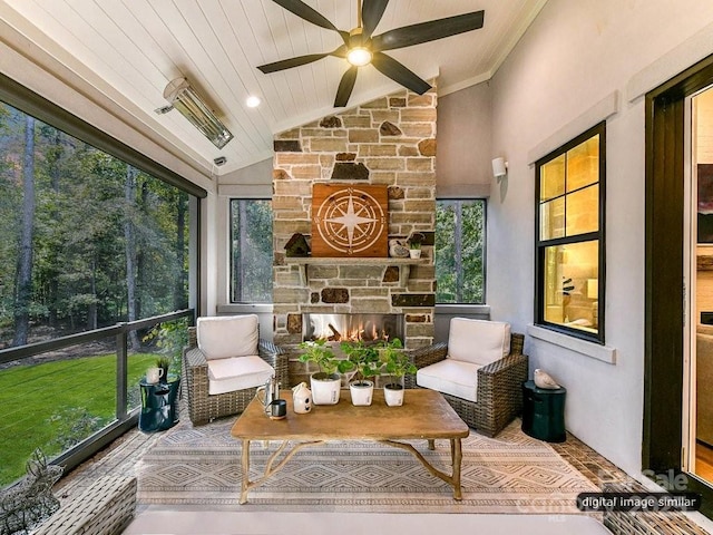 sunroom featuring a stone fireplace, ceiling fan, wooden ceiling, and vaulted ceiling