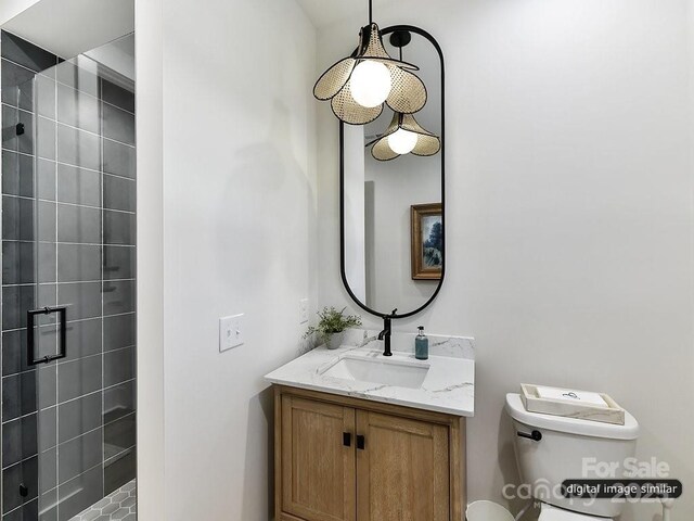bathroom with a shower stall, vanity, and toilet