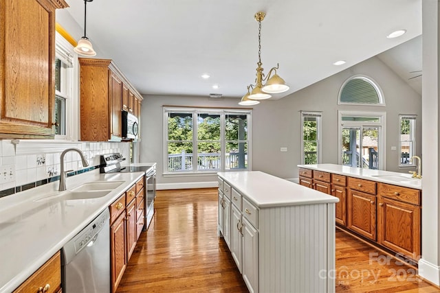 kitchen with backsplash, sink, stainless steel appliances, and decorative light fixtures