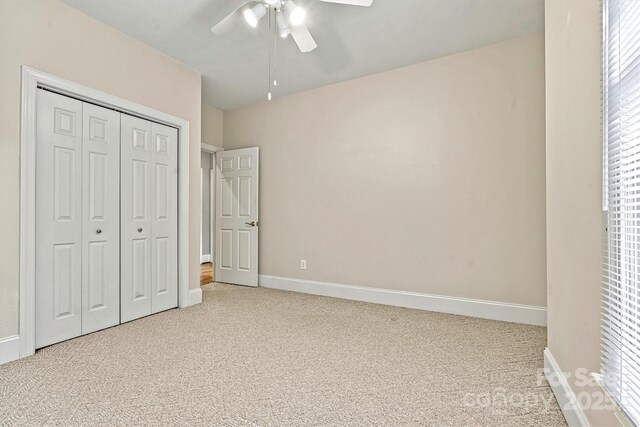 unfurnished bedroom featuring ceiling fan, carpet floors, multiple windows, and a closet