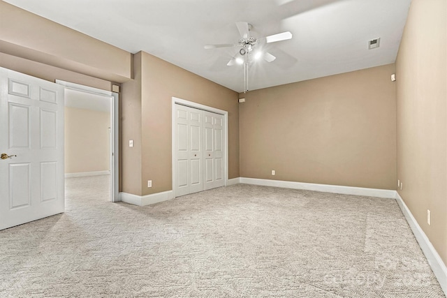 unfurnished bedroom featuring light carpet, a closet, and ceiling fan