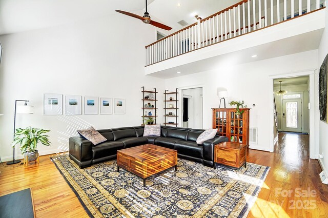 living room with hardwood / wood-style floors, ceiling fan, and a towering ceiling