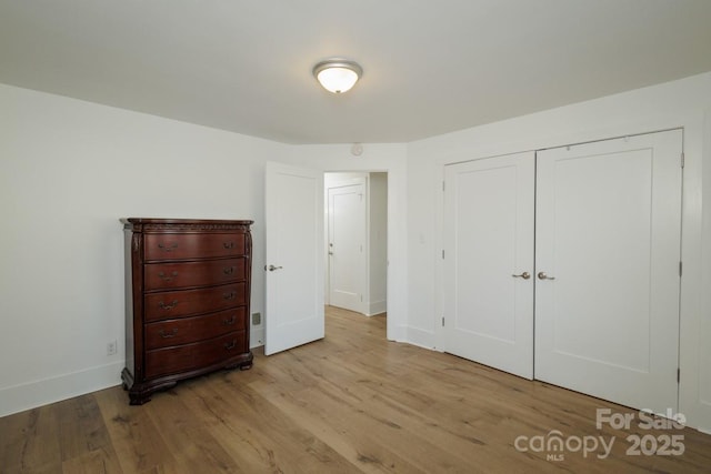 unfurnished bedroom with a closet and light hardwood / wood-style floors