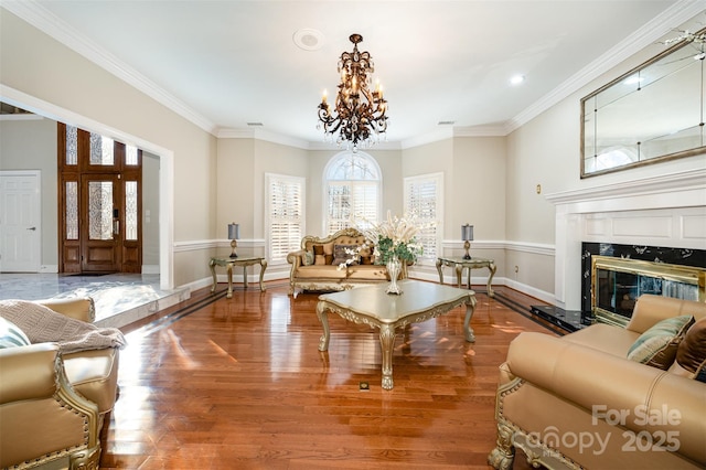 living room with ornamental molding, a fireplace, hardwood / wood-style floors, and a notable chandelier