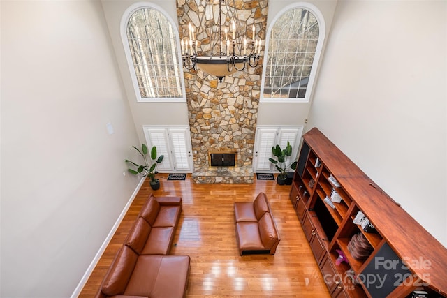 living room with light hardwood / wood-style floors, a high ceiling, and a stone fireplace