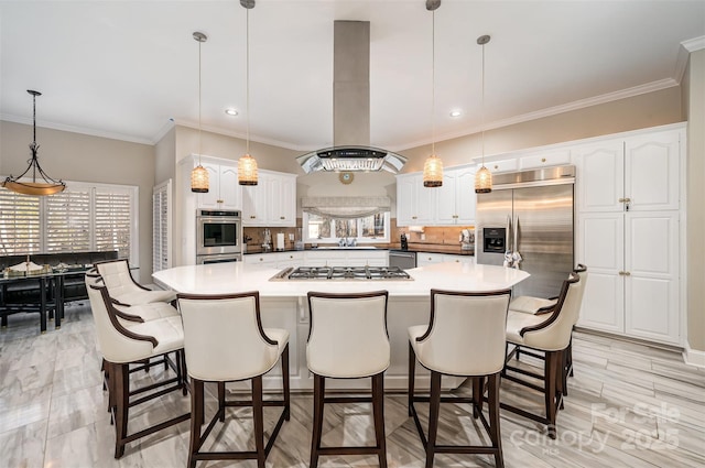 kitchen featuring white cabinetry, appliances with stainless steel finishes, island exhaust hood, and hanging light fixtures