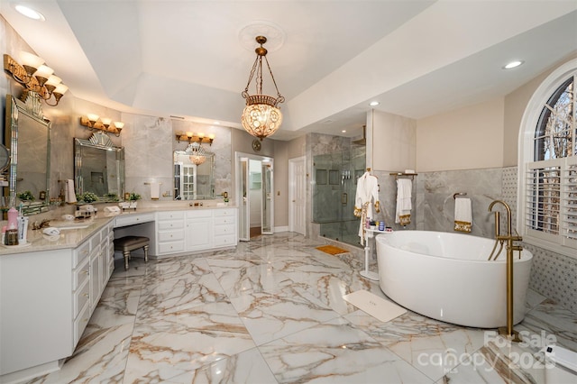 bathroom with vanity, independent shower and bath, a tray ceiling, and a notable chandelier