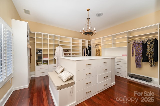 walk in closet featuring dark hardwood / wood-style flooring and a notable chandelier