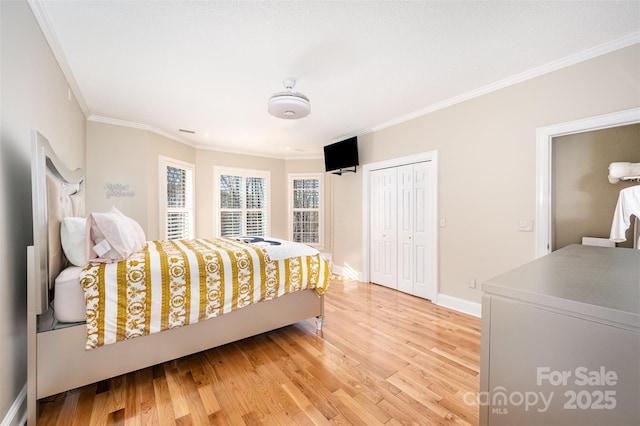 bedroom with light wood-type flooring, a closet, and ornamental molding