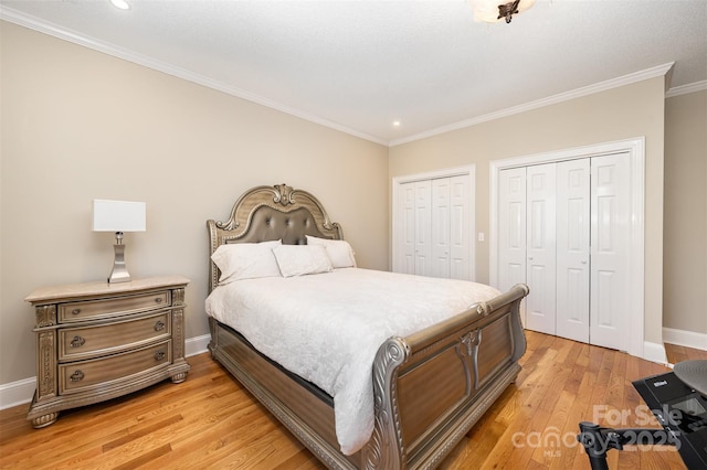 bedroom featuring multiple closets, ornamental molding, and light hardwood / wood-style floors