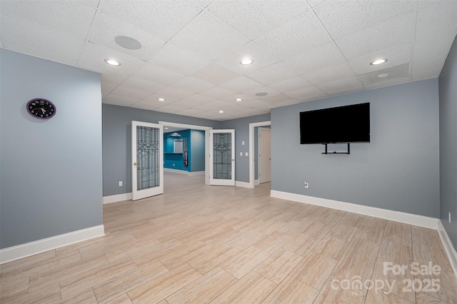 unfurnished living room featuring french doors and a drop ceiling