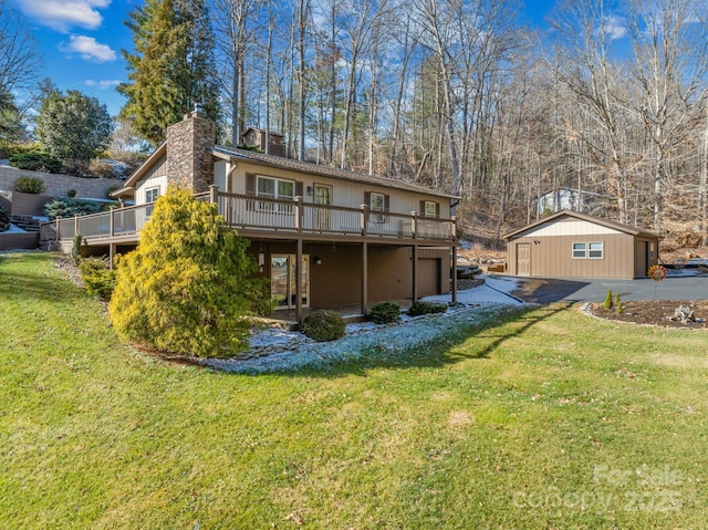 back of property featuring a deck, a yard, and an outdoor structure