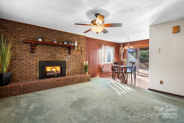 unfurnished living room featuring a brick fireplace, a textured ceiling, carpet floors, and ceiling fan