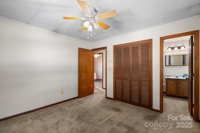 unfurnished bedroom with connected bathroom, a closet, light colored carpet, ceiling fan, and a textured ceiling