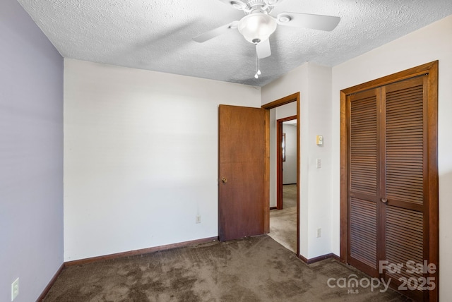 unfurnished bedroom with a textured ceiling, ceiling fan, a closet, and dark carpet