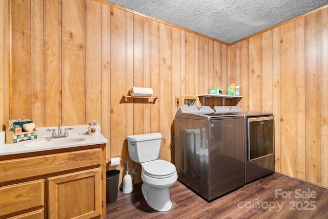 washroom with sink, wooden walls, separate washer and dryer, and dark wood-type flooring