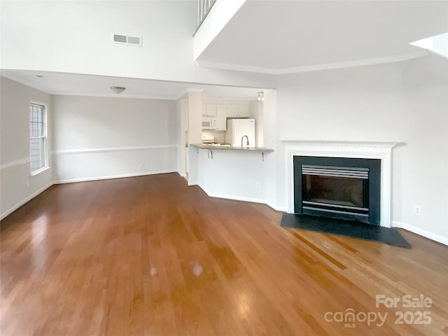 unfurnished living room featuring hardwood / wood-style flooring and ornamental molding