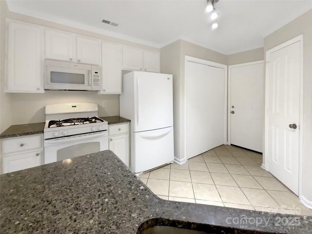 kitchen with light tile patterned floors, white appliances, white cabinetry, and dark stone countertops