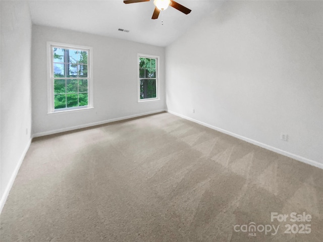 carpeted spare room featuring baseboards, ceiling fan, vaulted ceiling, and visible vents