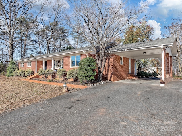 ranch-style house featuring aphalt driveway, a carport, and brick siding