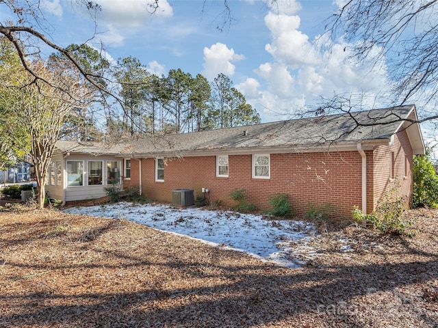 back of house featuring central AC unit and brick siding