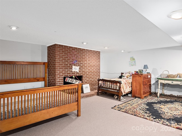 bedroom with carpet floors, a large fireplace, and brick wall