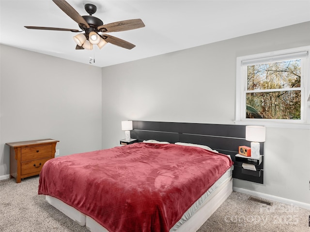 bedroom with light carpet, a ceiling fan, visible vents, and baseboards