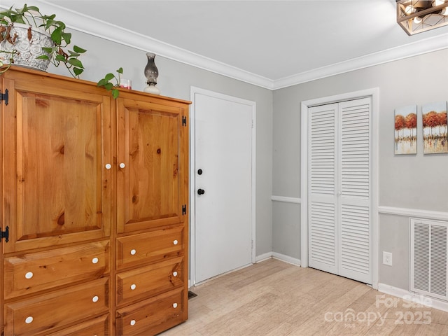 bedroom featuring light wood finished floors, baseboards, visible vents, ornamental molding, and a closet