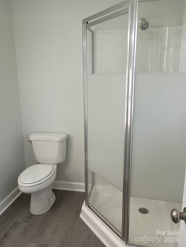 bathroom featuring toilet, a shower with door, and hardwood / wood-style floors