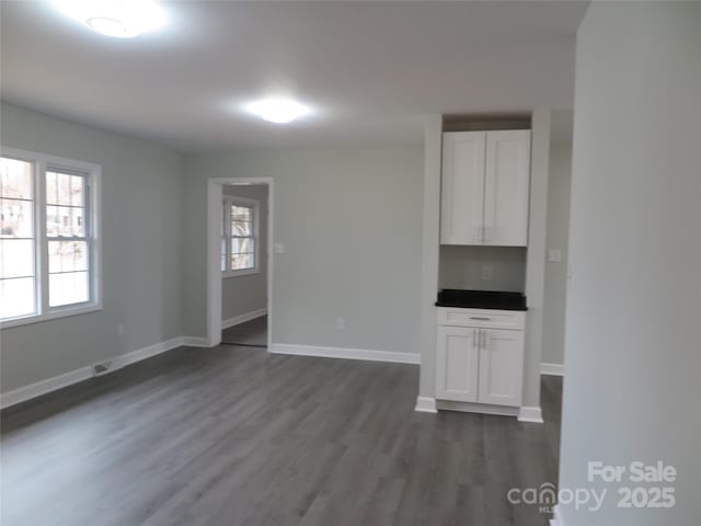 unfurnished living room featuring plenty of natural light and dark hardwood / wood-style floors