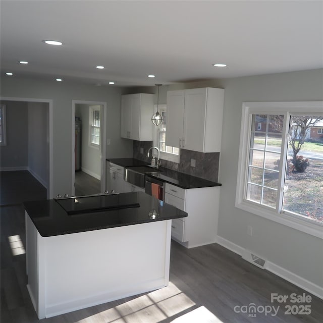 kitchen with dark hardwood / wood-style floors, stovetop, sink, white cabinets, and decorative backsplash