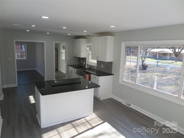 kitchen featuring dark wood-type flooring, sink, black cooktop, white cabinets, and backsplash