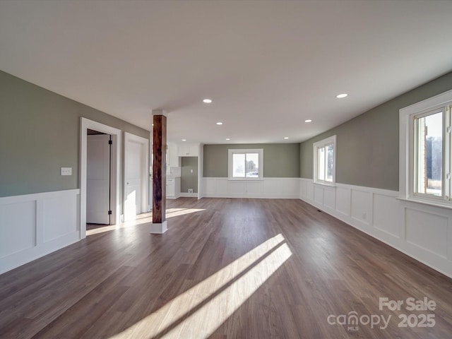 unfurnished living room featuring plenty of natural light and dark wood-type flooring