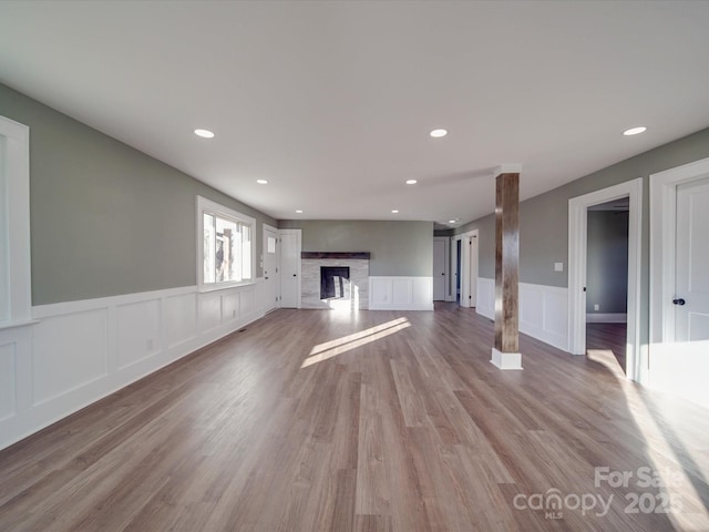 unfurnished living room featuring light hardwood / wood-style floors and ornate columns