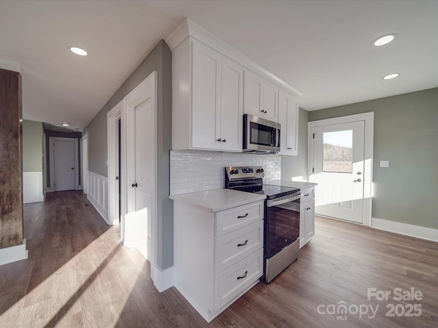 kitchen featuring decorative backsplash, light hardwood / wood-style flooring, white cabinets, and stainless steel appliances