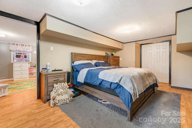 bedroom featuring hardwood / wood-style flooring, a textured ceiling, crown molding, and a closet