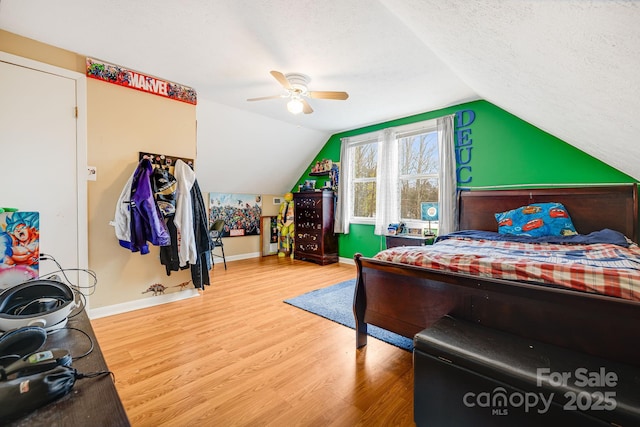 bedroom featuring ceiling fan, wood-type flooring, a textured ceiling, and lofted ceiling