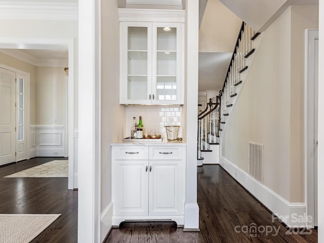 bar with white cabinets, decorative backsplash, dark hardwood / wood-style flooring, and ornamental molding