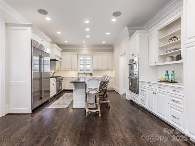 kitchen with white cabinets, a center island, a kitchen breakfast bar, dark hardwood / wood-style floors, and high quality appliances