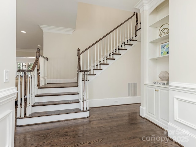 stairs with built in features, crown molding, and hardwood / wood-style floors