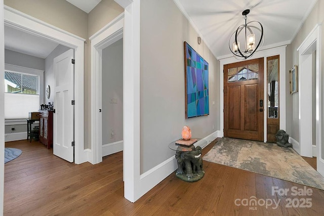 entrance foyer featuring an inviting chandelier, crown molding, and hardwood / wood-style floors