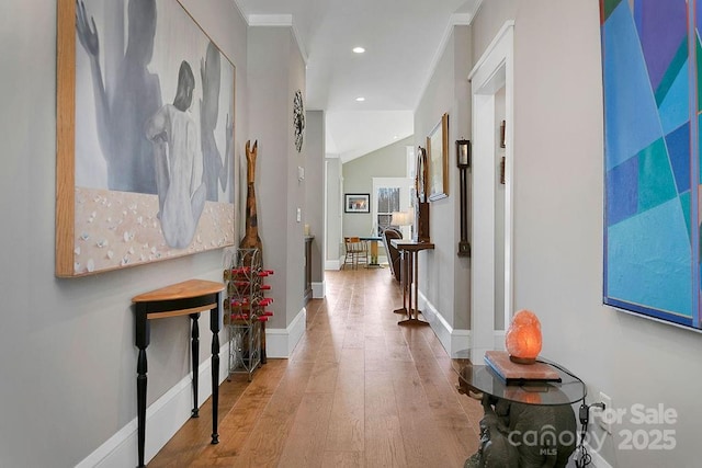 corridor featuring ornamental molding, wood-type flooring, and lofted ceiling