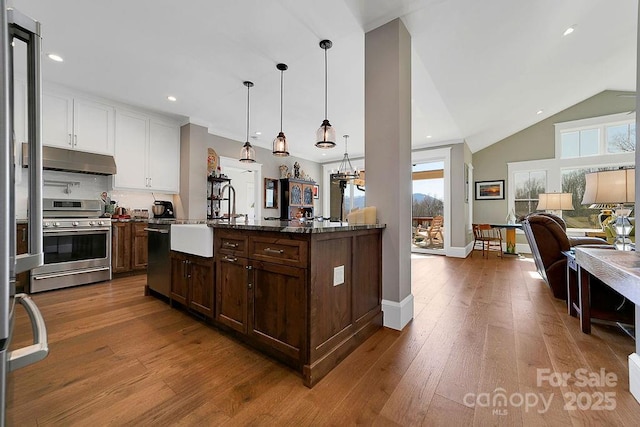 kitchen with sink, white cabinetry, hanging light fixtures, appliances with stainless steel finishes, and a kitchen island with sink