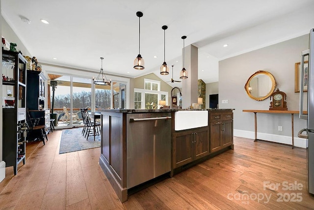 kitchen featuring decorative light fixtures, dishwasher, dark brown cabinets, a center island with sink, and light hardwood / wood-style flooring