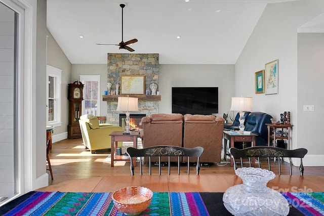 living room with ceiling fan, wood-type flooring, a fireplace, and vaulted ceiling