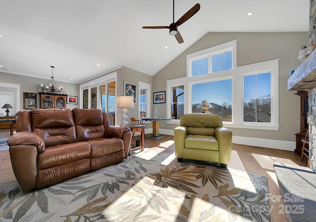 living room with ceiling fan with notable chandelier, a wealth of natural light, lofted ceiling, and light wood-type flooring